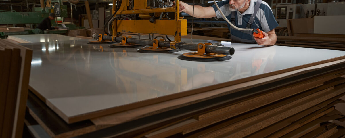 Concentrated grey-haired man leaning on mdf plate while touching new equipment