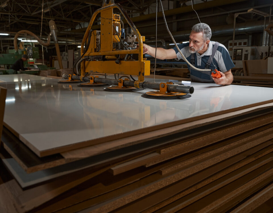 Concentrated grey-haired man leaning on mdf plate while touching new equipment