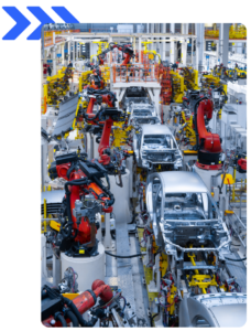 Interior of a modern factory with robotic arms assembling vehicles.