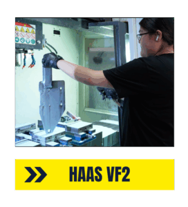 Machining Small Precision Parts with HAAS VF2 - Accurate Metal Stamping operator loading a steel part into a HAAS VF2 CNC mill